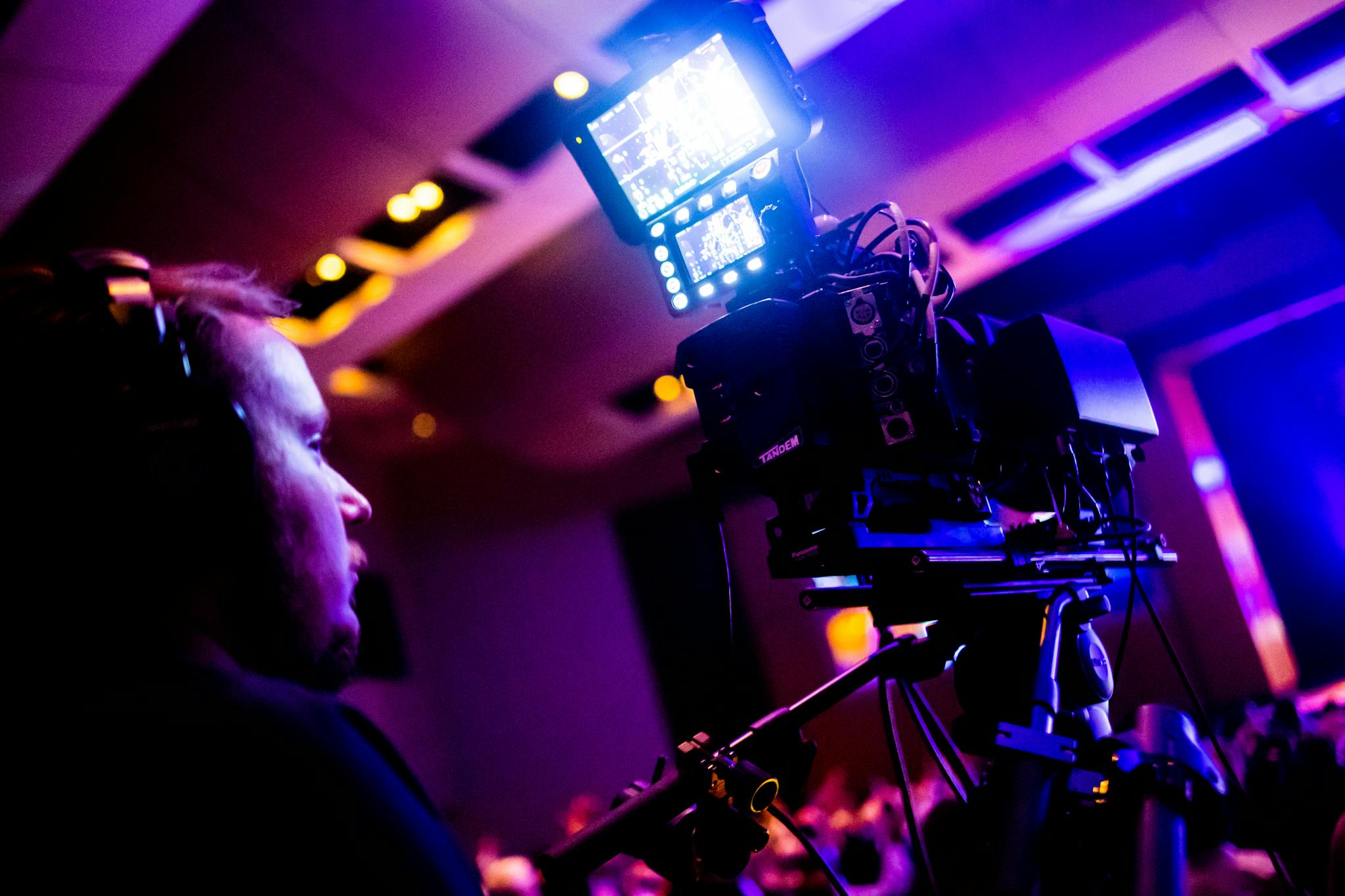 A professional cameraman operating a camera during a vibrant nightlife event indoors.